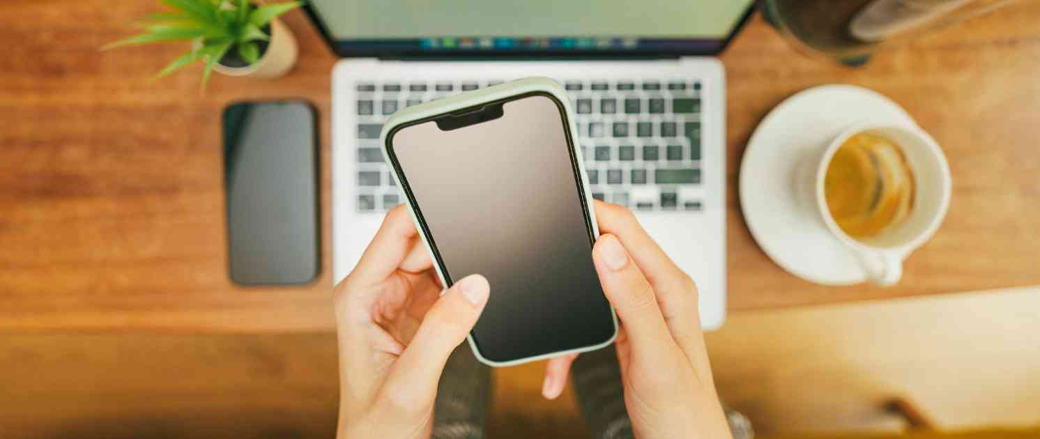 Mann sitzt auf der Couch am Laptop und hat Kopfhörer auf