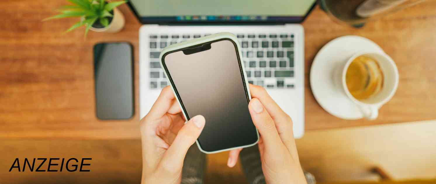 Mann sitzt auf der Couch am Laptop und hat Kopfhörer auf